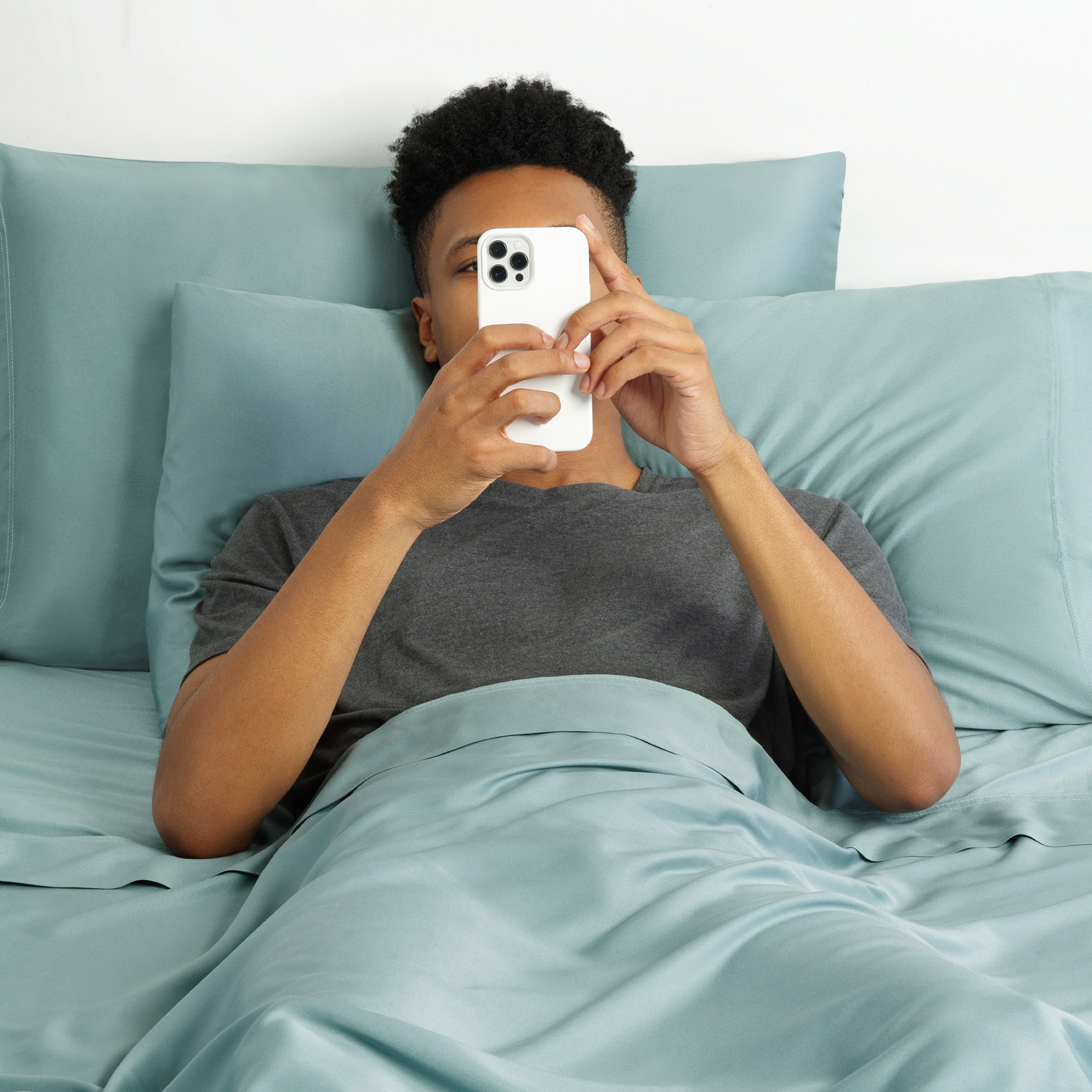 guy laying in a bed on his phone