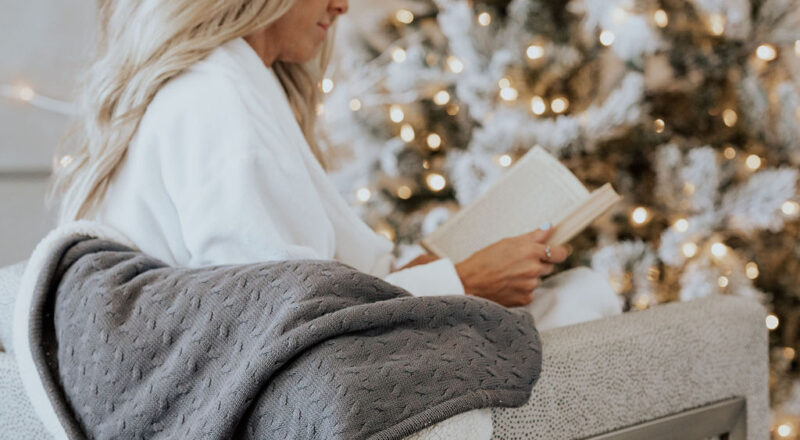 model wearing cariloha robe while reading a book next to a christmas tree