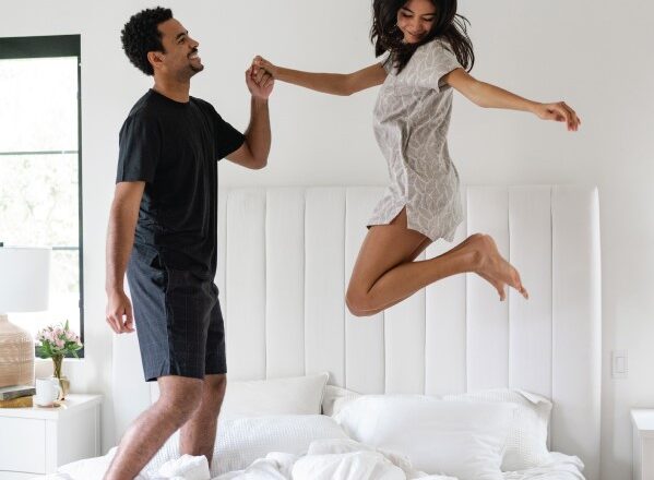 mand og kvinde hopper på en seng med cariloha-lagner