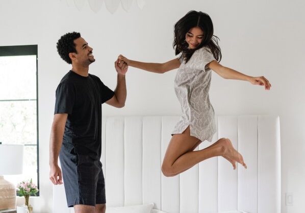 man and woman jumping on a bed with cariloha sheets